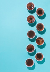 Vertical series of coffee cups on blue background with copy space
