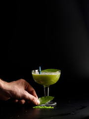 Cold green apple cocktail with green biscuit. Restaurant serve, on a black background.
