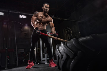 Fototapeta na wymiar Young handsome athlete bodybuilder, weightlifter, doing crossfit, with a sledgehammer, in a modern gym. Concept-strength, beauty, power, sport, health, sports nutrition, diet, styroydy, scales.