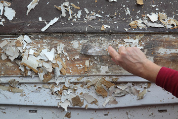 Vintage window restoration, worker using putty knife to remove old paint