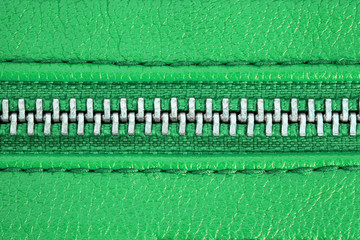 Zipper tightly closed binding together two layers of green fabric textile and green leather under...