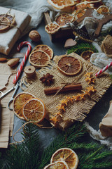 Christmas or New Year composition with handmade gifts, dry oranges, cinnamon, fir tree on dark stone table. Holidays preparations, hugge concept, selective focus