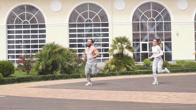 Cheerful caucasian male and female dancers performing a sportive dance on Town squre with beautiful building background.