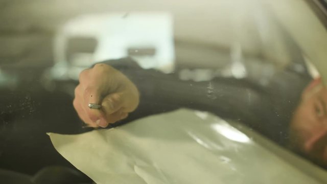 Close-up of a man professionally in the workshop engaged in eliminating cracks on the windshield of the car. Filling the crack with polymer
