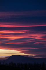 Fototapeta premium Fluffy orange and purple clouds over the mountain