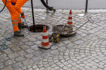 sewerage worker on street cleaning pipe