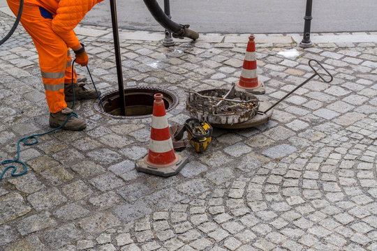 Sewerage Worker On Street Cleaning Pipe