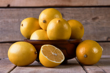 Fresh lemons in a wooden bowl on wood background with copy space