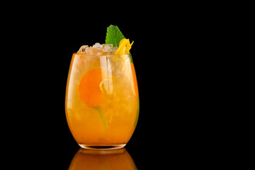 Closeup glass of orange tangerine fresh juice with ice cubes isolated at black background.