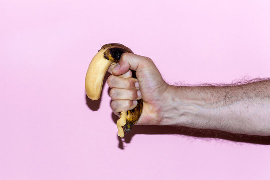 Hand Crushing Banana on Pink