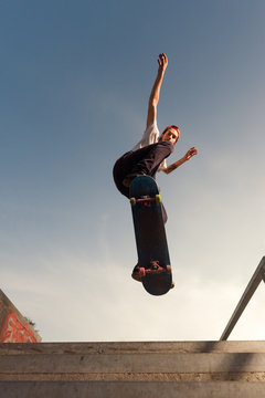 Male skater flying in midair jumping over concrete stairs