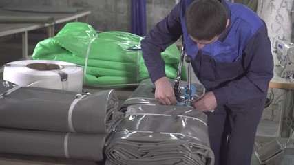 man warehouse worker is engaged in the packaging of plastic awning