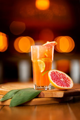 Glass of fresh orange juice with lemon, grapefruit and lime on a wooden board at festive blurred background.