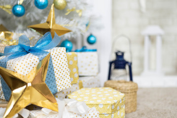 Fototapeta premium family holiday concept. Merry Christmas and Happy Holidays. Studio with Christmas decor. Winter home decor. Christmas tree, fireplace with firewood Boxes with gifts and golden and blue bows. Xmas