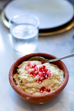 A bowl of hummus and pomegranate seeds