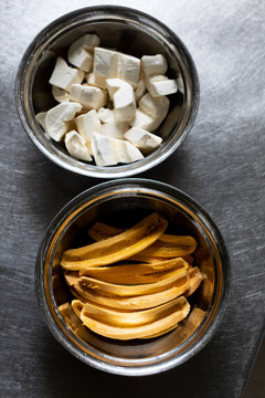 Pieces of a cassava root and slices of a plantain in bowls