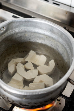 Cassava root in a bowl with water being cooked on a stove