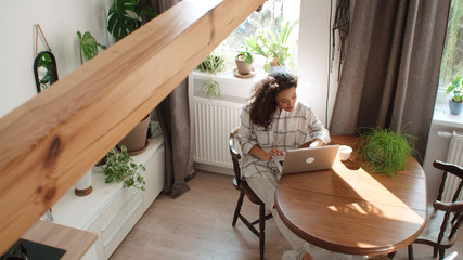 Charming young woman typing on laptop computer at home.