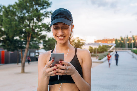 Sporty young woman texting on her smartphone