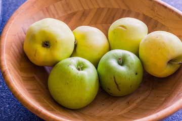 Six yellow-green apples lie in a wooden bowl. Natural and juicy fruits, full of vitamins. Collected in the garden with trees. Vegetarian Snacks