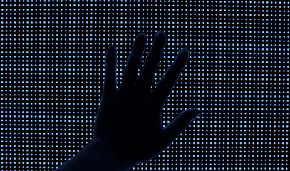 Hand on a big blue LED screen.