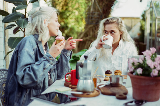 Two women looking at a tablet, working together and having breakfast