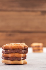 Shaped cookies with layers of chocolate filling, wooden background, vertical frame, copy space.