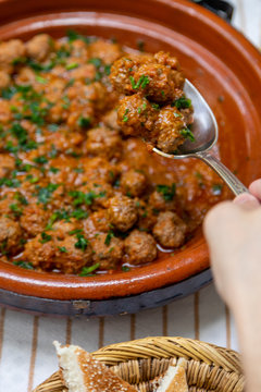Person scooping up meatballs to eat 
