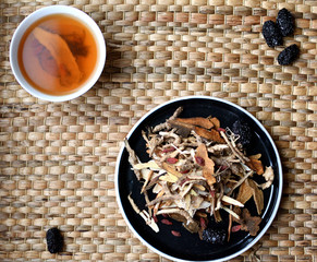 Chinese traditional medicine script. Herbal tea with jujubes, goji berries, gingseng roots and others on neutral background.