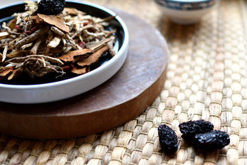Chinese traditional medicine script. Herbal tea with jujubes, goji berries, gingseng roots and others on neutral background.