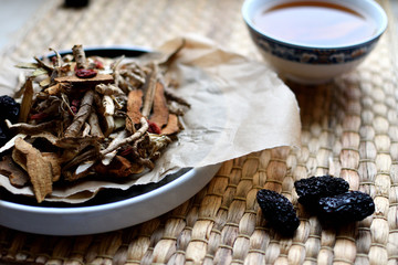 Chinese traditional medicine script. Herbal tea with jujubes, goji berries, gingseng roots and others on neutral background.