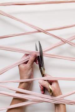 Hands Using Scissors To Cut Through A Tangle Of Silk Ribbon