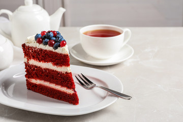 Plate with piece of delicious homemade red velvet cake on table. Space for text