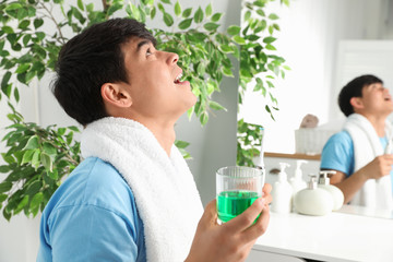 Man rinsing mouth with mouthwash in bathroom. Teeth care