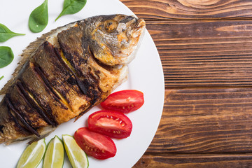 Fried fish dorado with lime , tomatoes and spinach