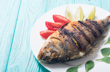 Fried fish dorado with lime , tomatoes and spinach