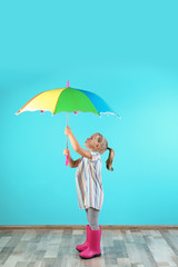 Little girl with rainbow umbrella near color wall