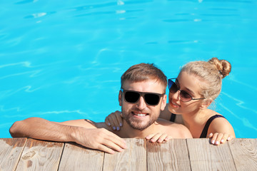 Obraz premium Happy young couple in swimming pool at resort