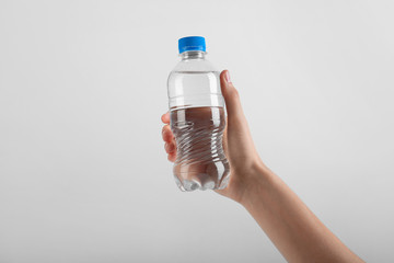 Woman holding plastic bottle with water on white background