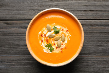 Bowl with tasty pumpkin soup on wooden table, top view