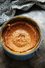Finishing freshly baked caramel cheesecake in cake mold on a dark background. Top view, vertical. Selective focus.