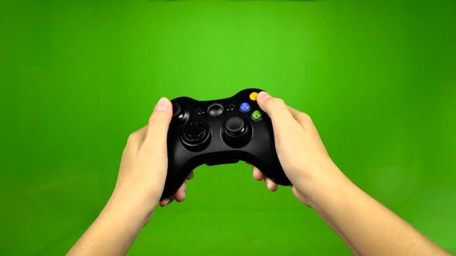 Hands of dedicated gamer using a game controller with green screen
