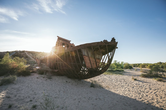 rusting hulk of abandoned trawler in desert at sunset