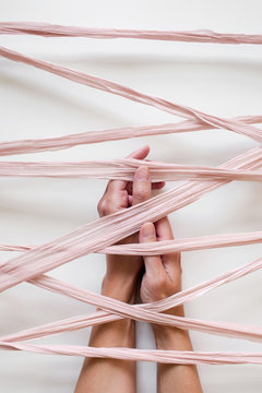 vertical image of folded hands caught under silk ribbon
