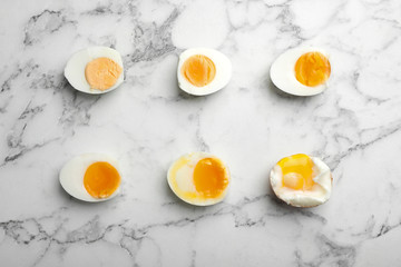 Various types of boiled eggs on marble background, flat lay. Cooking time