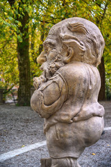 Fototapeta premium Stone statue of a dwarf. Marble sculpture of fairy gnome in Salzburg Mirabellgarten park, Salzburg, Austria