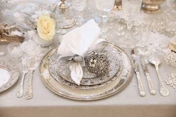 New year's table, beautiful plates and Cutlery white with silver with glass glasses