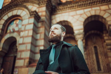 Handsome bearded man with mustache in front of church. Movember concept