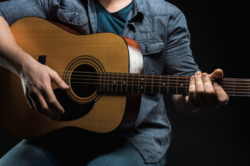 male hands play acoustic guitar