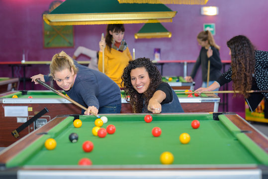 two female friends playing billiards